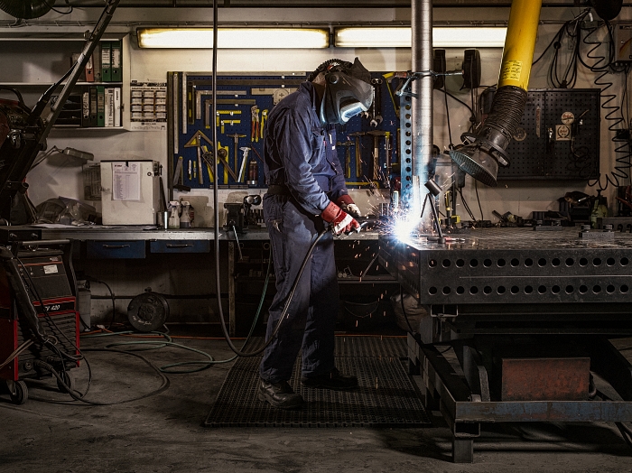 Our story: Man in protective wear welding metal